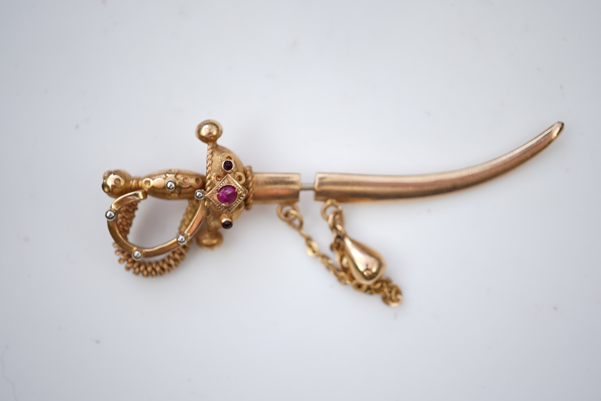 A gold and synthetic ruby jabot pin